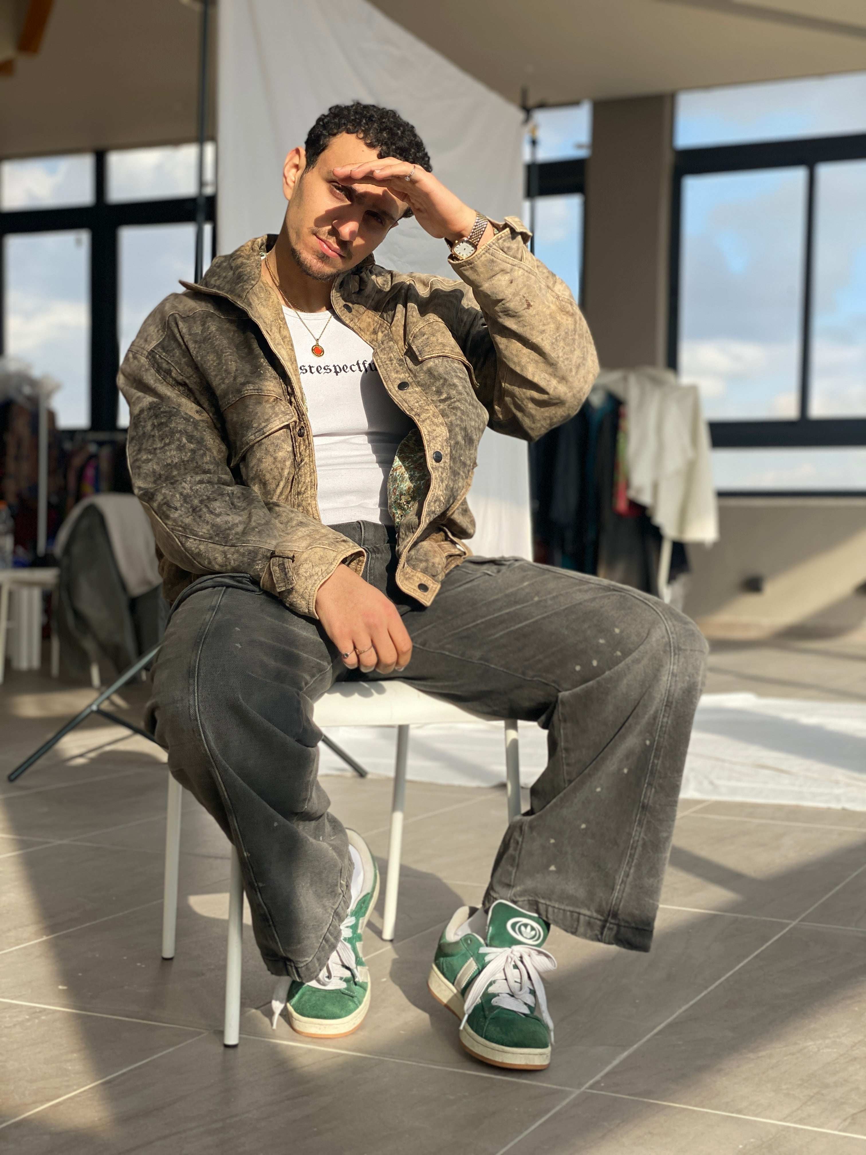 Man in vintage acid wash jacket, faded jeans, and green suede sneakers, styled for 90s Y2K fashion