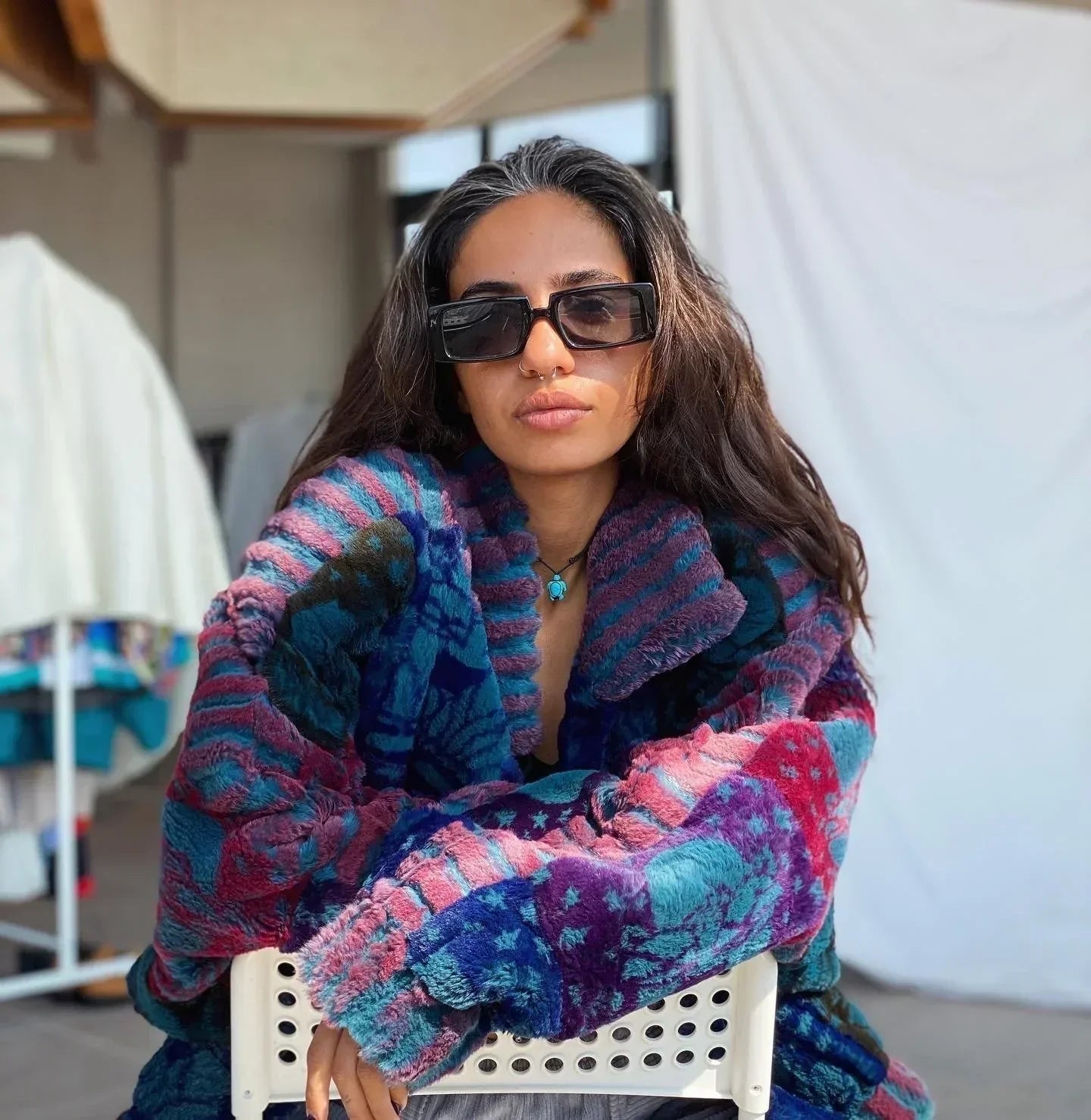 Woman wearing oversized multicolor vintage faux fur coat with floral patterns and black sunglasses indoors