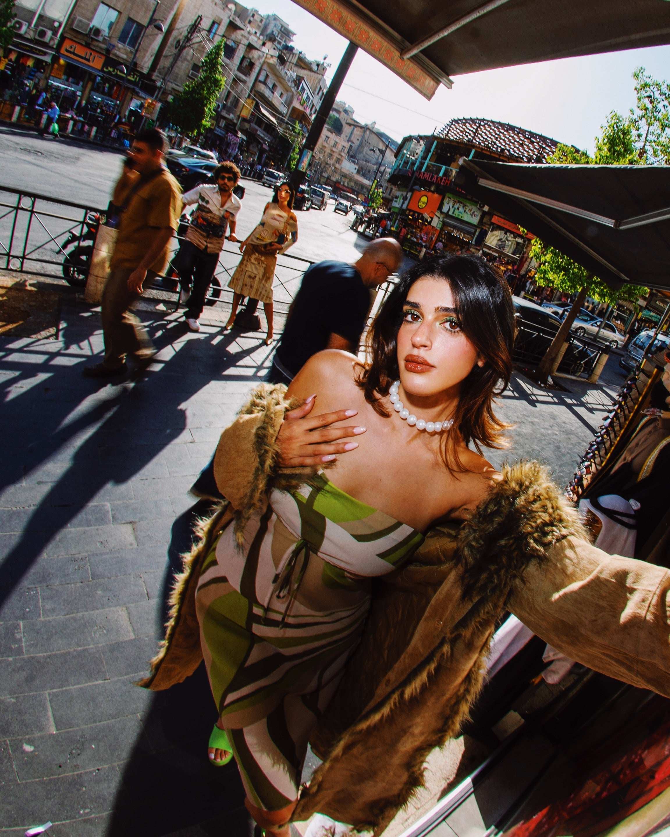 Woman in vintage green and white striped dress with faux fur coat, pearl necklace, street style fashion